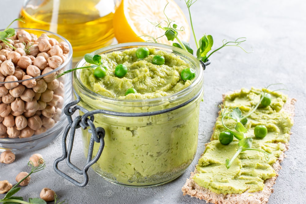 Green parsley hummus with chickpeas, green pea and homemade chickpeas on a table. Delicious healthy food