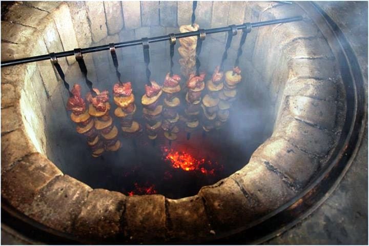 A fire pit with a lot of Armenian food on it.