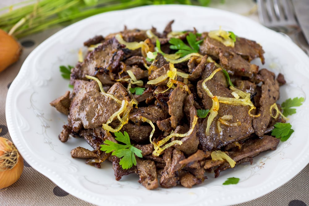 Armenian food fried Liver with Onions on a white plate decorated with parsley