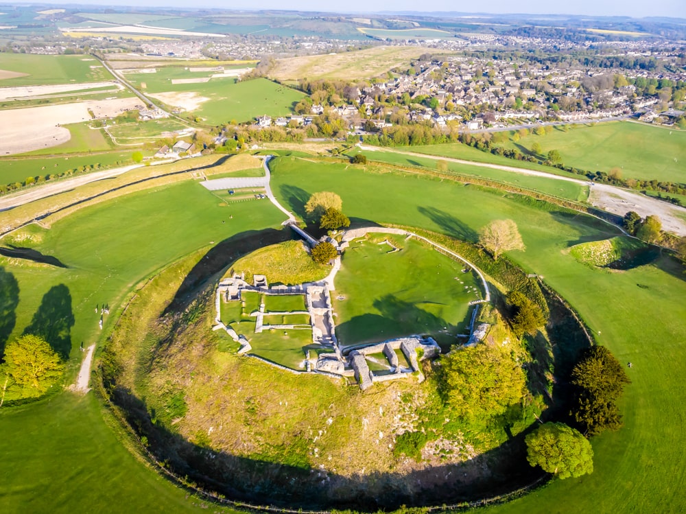 This is a drone shot of the ancient hillfort in Salisbury you can see the huge mound where the ruins of an ancient castle lie and the area is surrounded by what would have been a deep moat