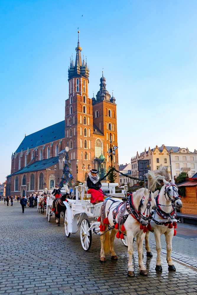 Krakow, Poland - December 20, 2016: Carriages for riding tourists on the background of Mariacki cathedral at main square in old city