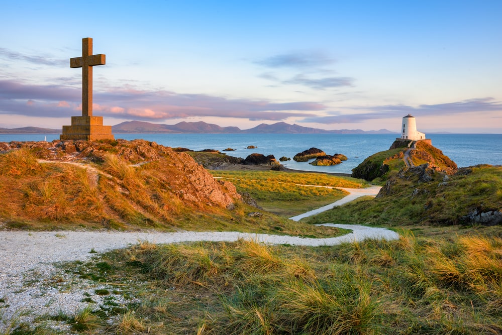 Twr Mawr lighthouse and the St Dwynwen's cross, the iconic landmarks on Anglesey island, panoramic view on sunset, Wales coast, United Kingdom. Best Things to do in Anglesey