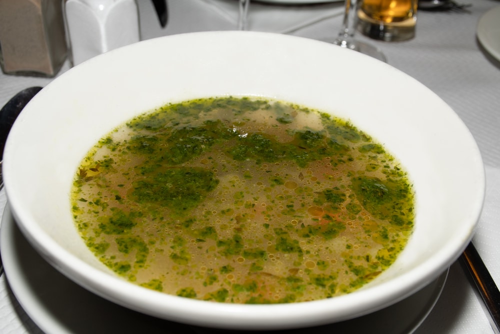Classic Soup au pistou (pesto) in a white bowl being served in a restaurant. traditional authentic recipe,Provencal flavours is a hearty and warming family meal. Soupe au pistou, fresh vegetable soup