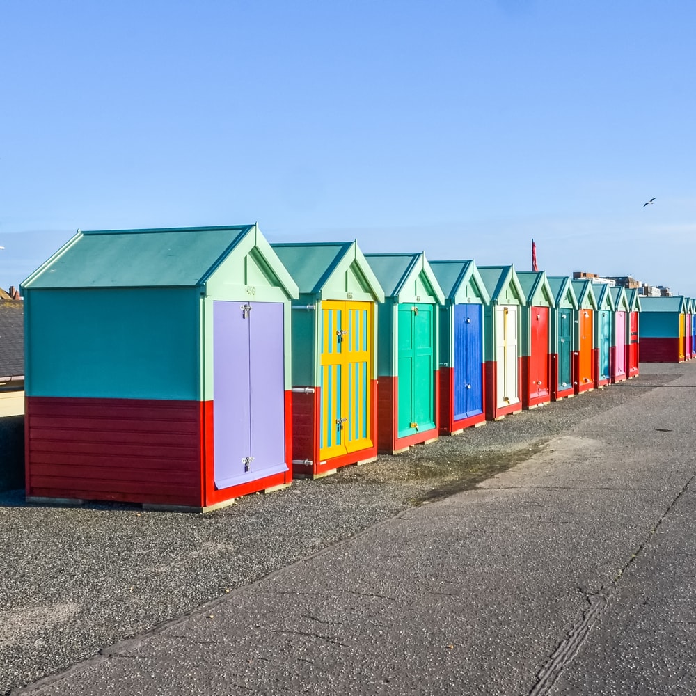 Staycations in the UK Row of beach huts on sea front in Worthing, Sussex, England