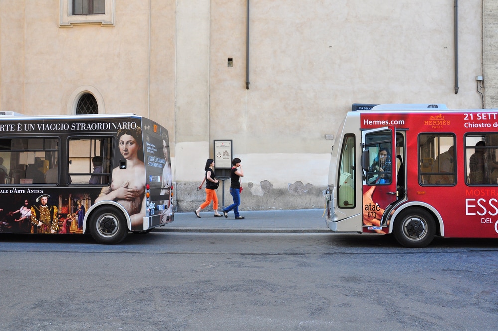 Buses pick up the passengers on the street of Rome. Public Transportation in Italian capital includes the metro, buses and trams.