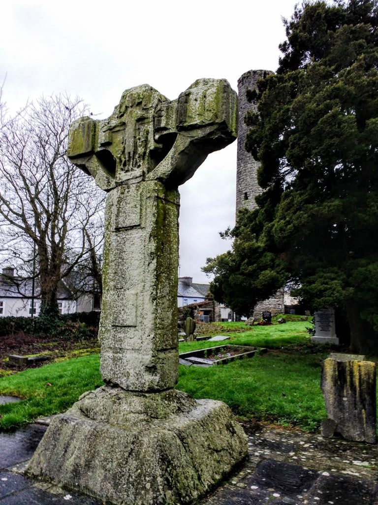 One of several broken celtic crosses at Kells Ireland. In the background you can see a Round Tower. The cross itself is quite plain and on the circular round centre of the cross is a carved image of Christ's crucifiction
