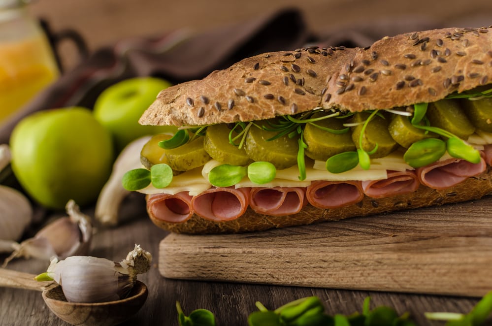 Baguette with the Prague ham, pickles, microgreens healthy herbs and emmental cheese