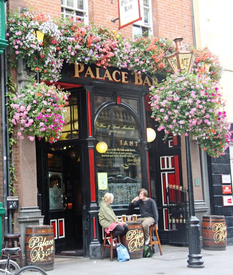 Best Day Trips from Dublin  The Palace Pub in Dublin City with hanging baskets of flowers and two people having a pint at a table outside