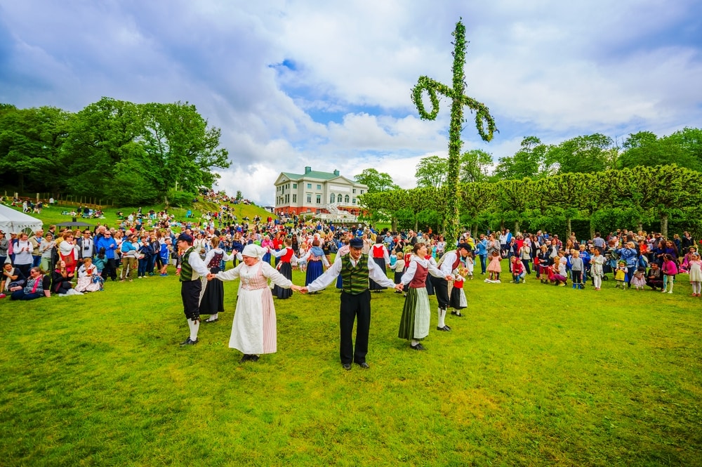 Unknown dancers in traditional swedish dress dancing around the maypole for Midsummer celebration in Gunnebo Castle