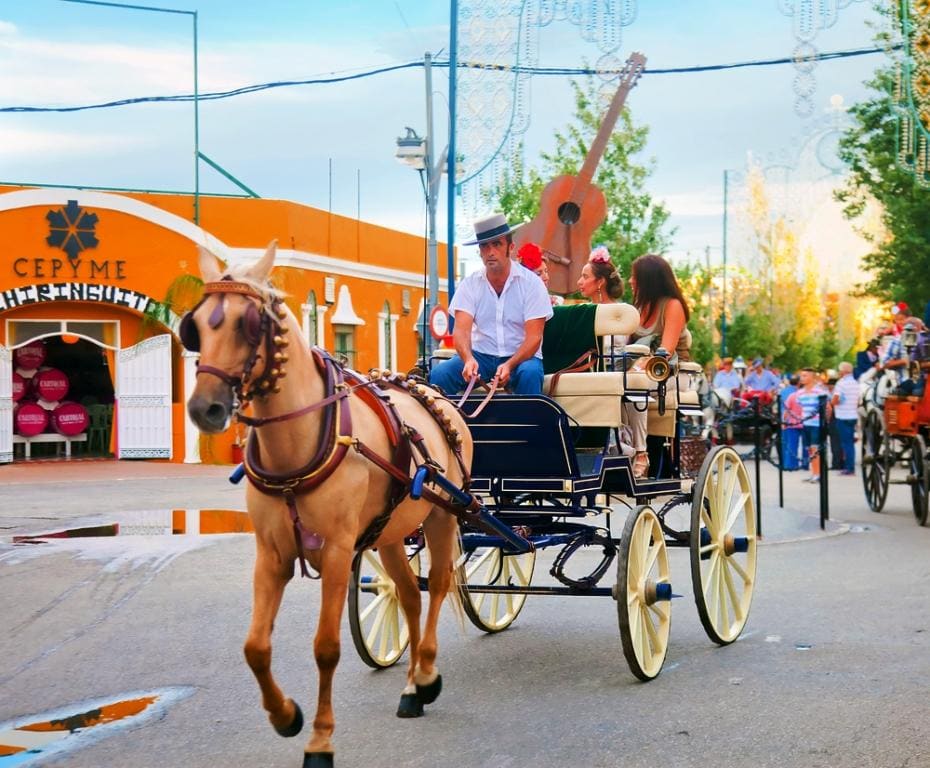 Man working as a coachman at fair in Spain driving a horse and open carriage with two passengers 