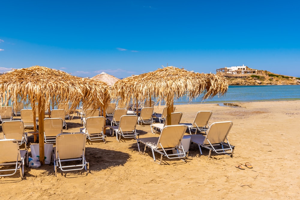 Sunbeds with umbrellas on Agios Georgios beach, very popular resort on Naxos island, Greece.