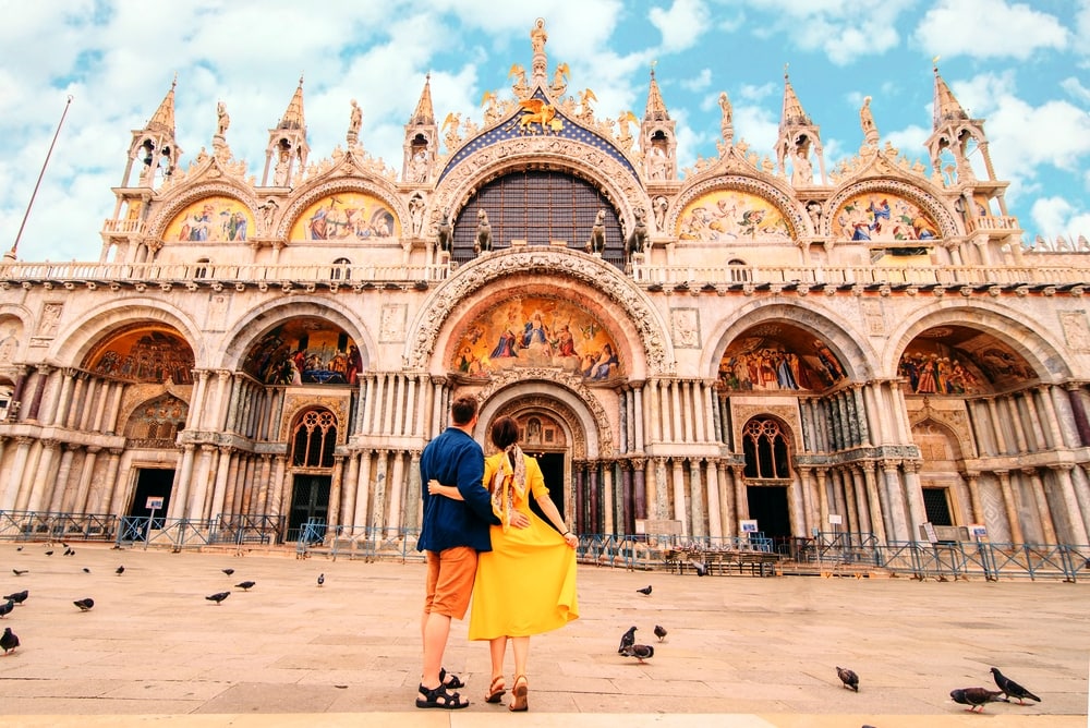 young pretty couple posing in front of saint marks basilica venice italy