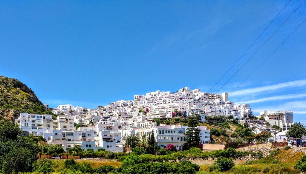 A cluster of white buildings sits on a hillside under a clear blue sky. Mojacar old town sits at the top