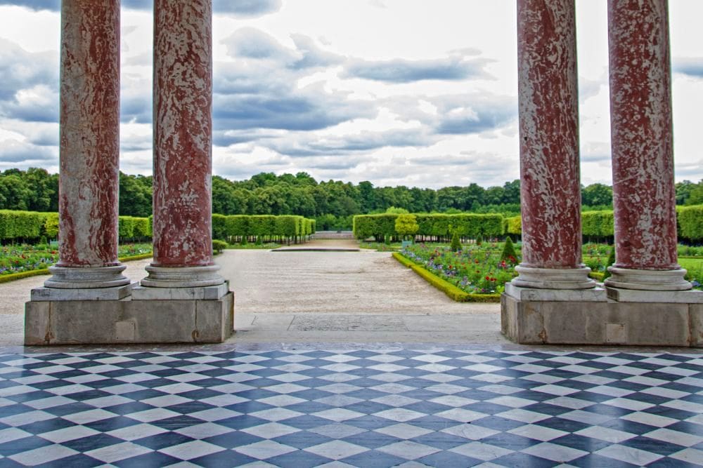 The Grand Trianon at Versailles with marlbe columns and a diamond checkerboard terrace in black and white overlooking the stunning gardnes