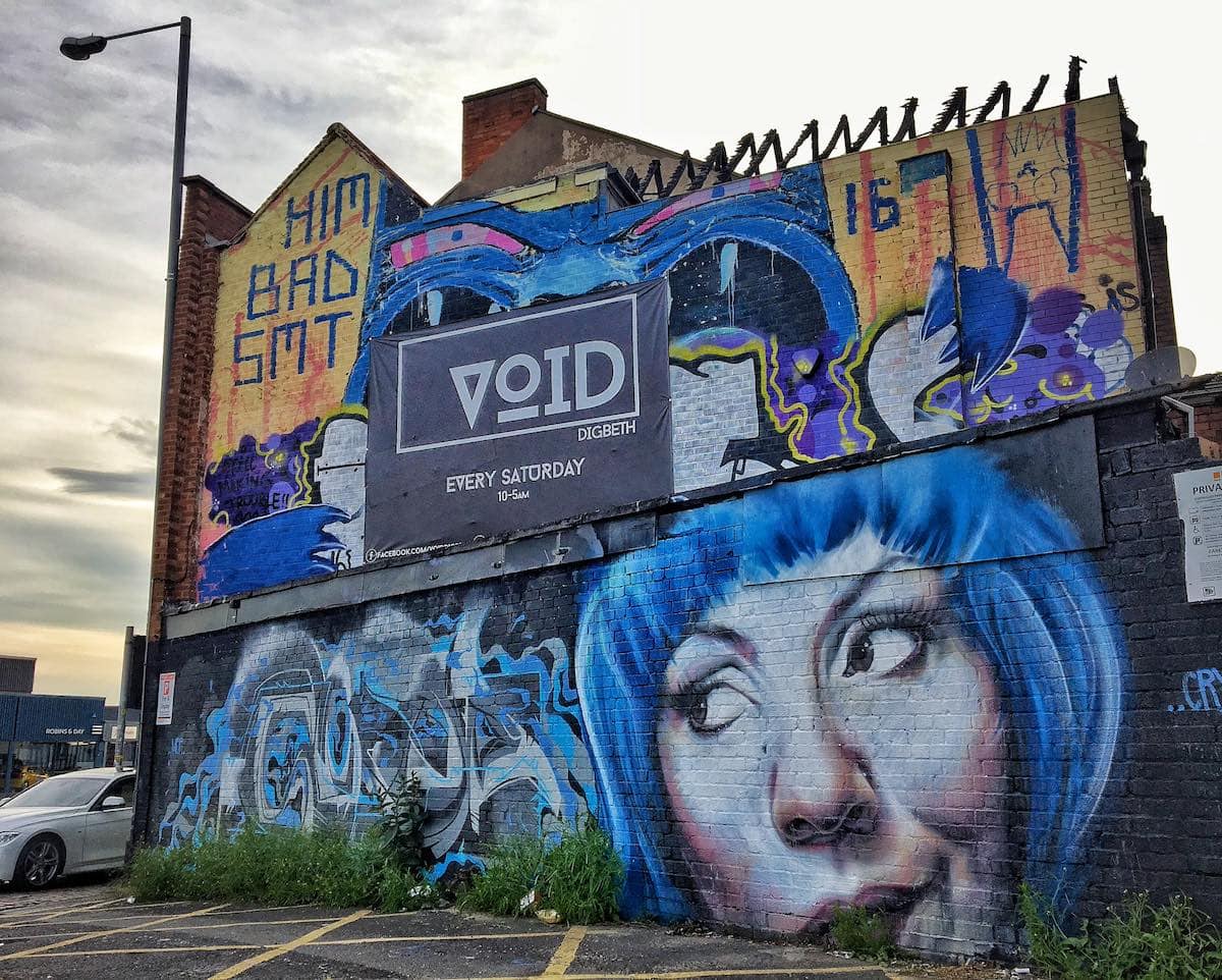 A building with graffiti on it and a blue haired girl, showcasing urban art in Birmingham.