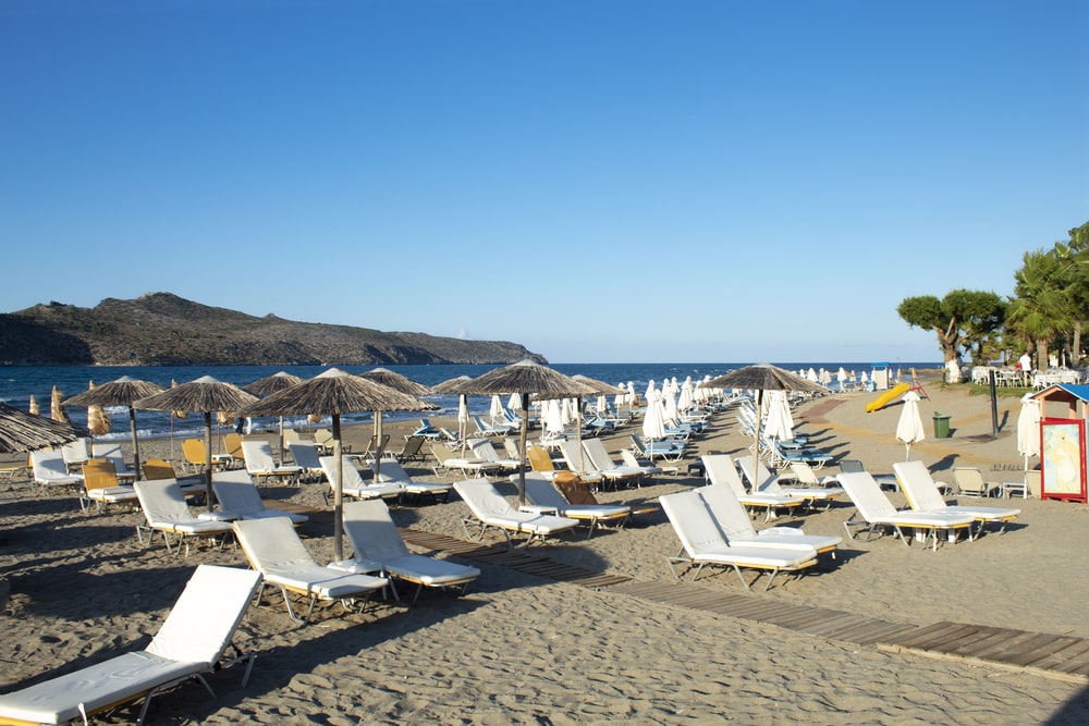Chania offers a stunning beachscape adorned with comfortable chairs and colorful umbrellas, perfect for relaxation and leisure. Beautiful Greek beach scene, Agia Marina, Chania, Crete Sun loungers on the sands Peaceful seaside scene Clear blue skies