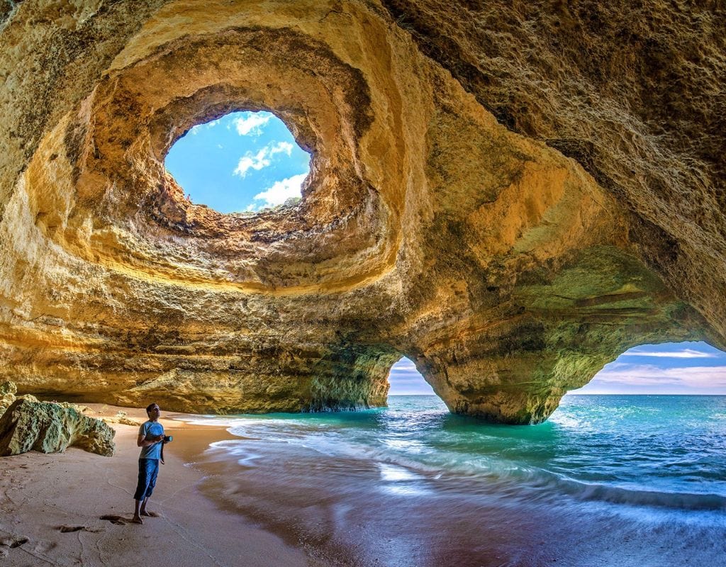 A person standing inside a cave on one of the best beaches in Portugal.