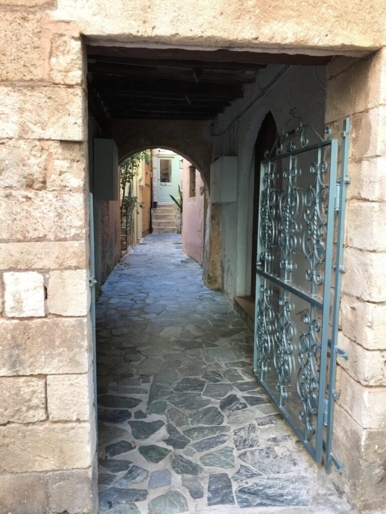 A stone walkway with a gate and a building.