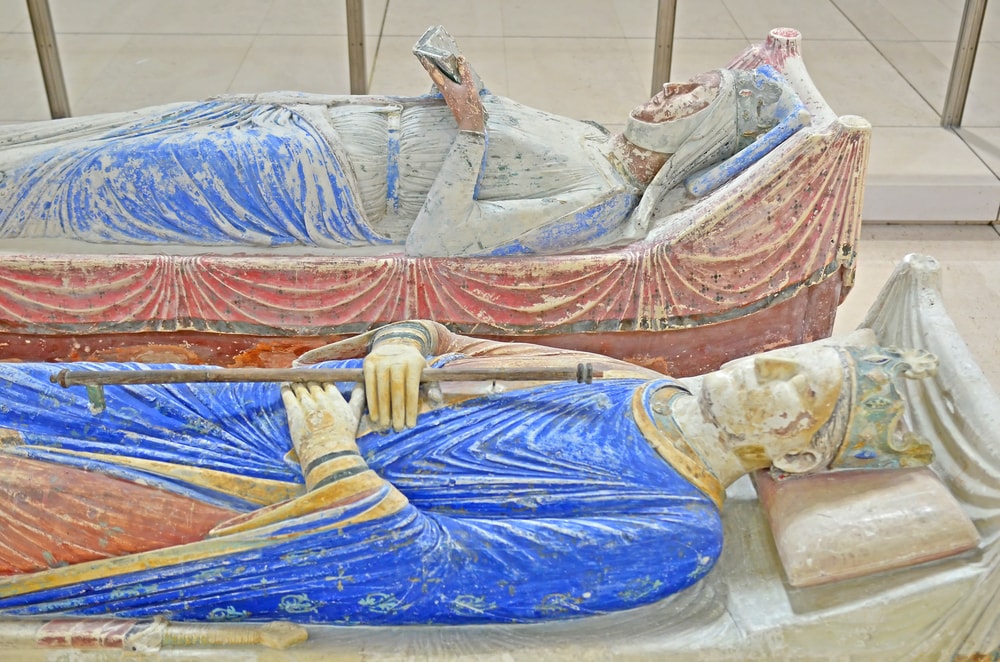 The tombs of King Henry II and Queen Eleanor of Aquitaine in Fontevraud Abbey. Two statues of a man and a woman laying on top of each other at Fontevraud Abbey.