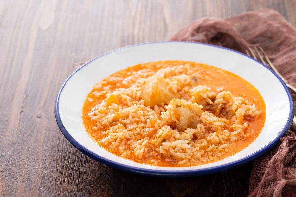 A bowl of Portuguese stew on a wooden table.