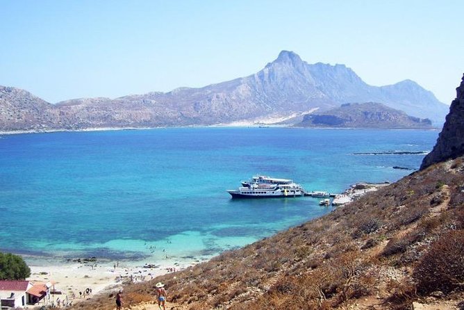 A boat is docked at a beach near a mountain, offering picturesque activities for tourists to enjoy while visiting Chania.