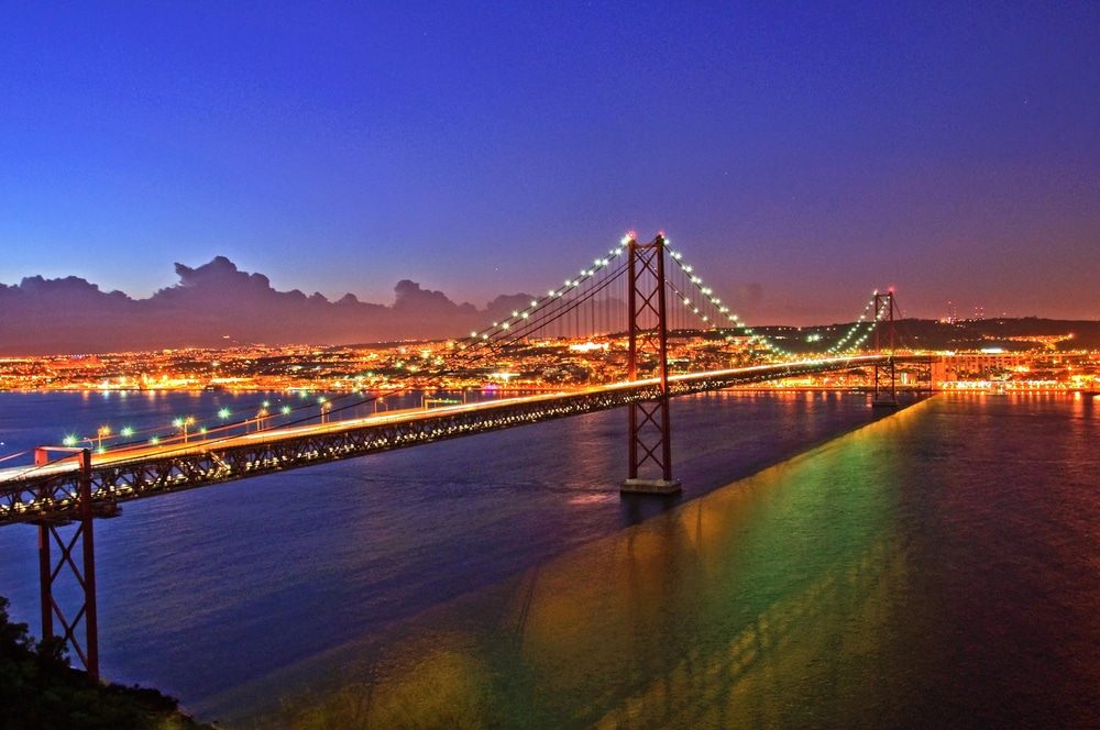 The lisbon bridge is lit up at night in lisbon, portugal.