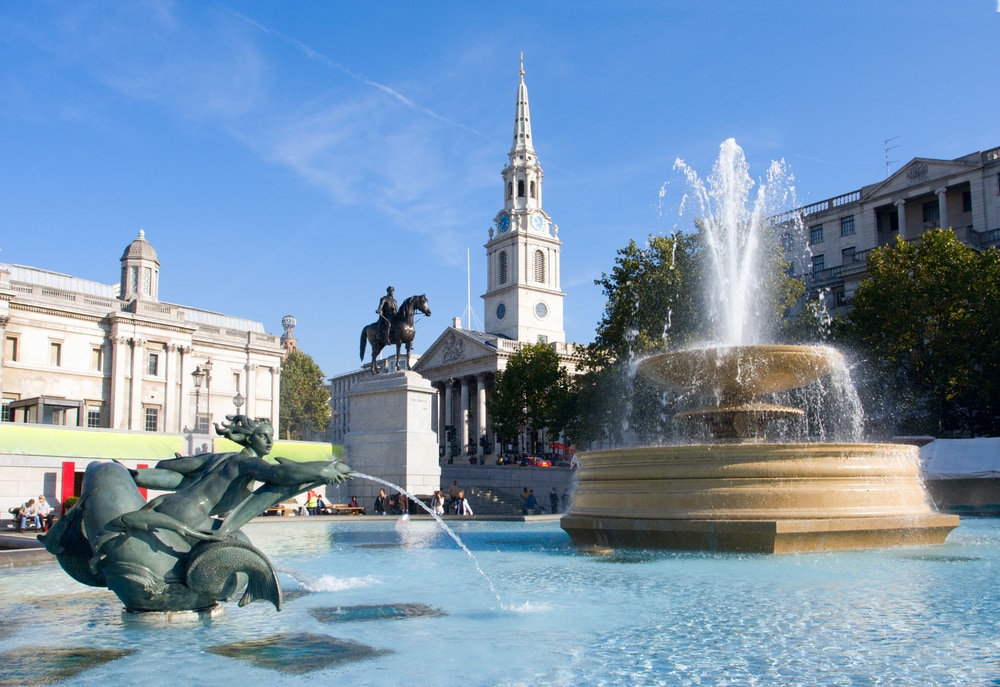 A fountain in front of a building in Trafalgar Square.