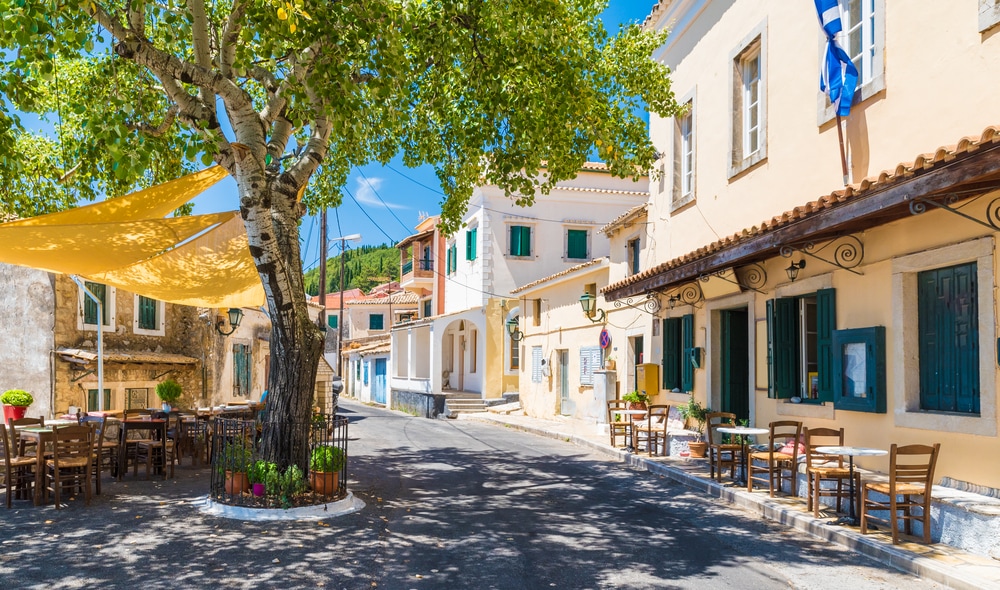 Central square of Lakones Village near Paleokastritsa, Corfu island, Greece. One of the best things to do in Corfu is spotting a yellow umbrella hanging on a tree. 