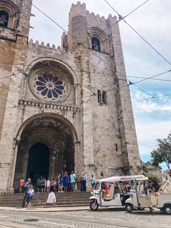 Sé de Lisboa, also known as the Lisbon Cathedral is the oldest church in the city. A group of people are standing in front of a cathedral.