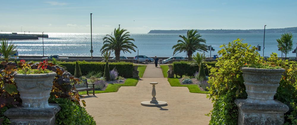 Italian gardens at Torre Park in Torquay Devon. The garden path runs down to the sea surrounded by palm trees
