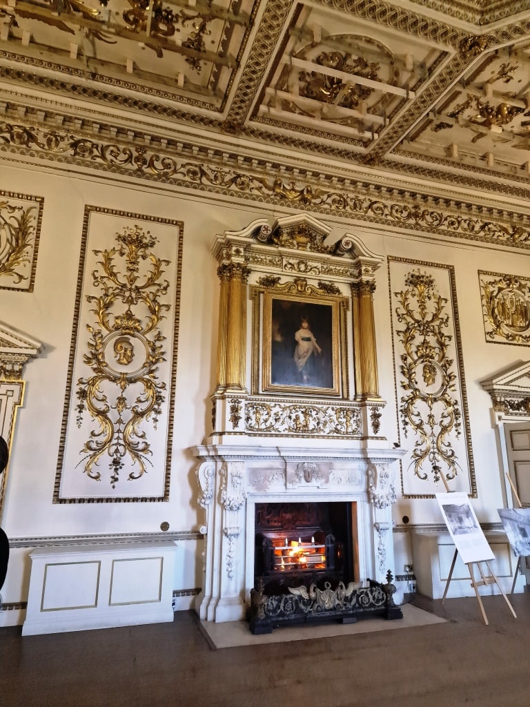 An ornately decorated room in an English manor house with a fireplace.