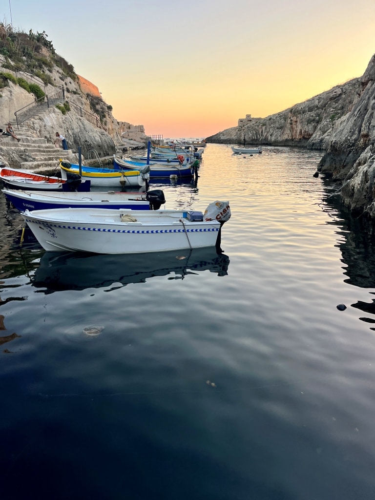 Boats moored in a calm cove at sunset.