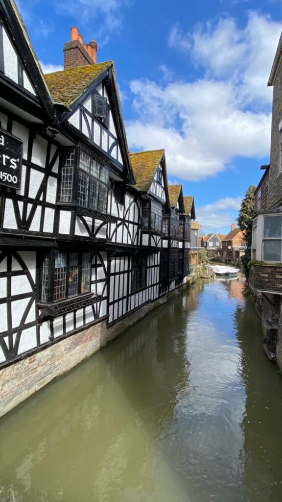 Half-timbered buildings lining a narrow canal offering Canterbury boat trips.