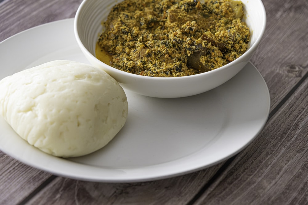 A plate of West African egusi soup with a side of pounded yam.