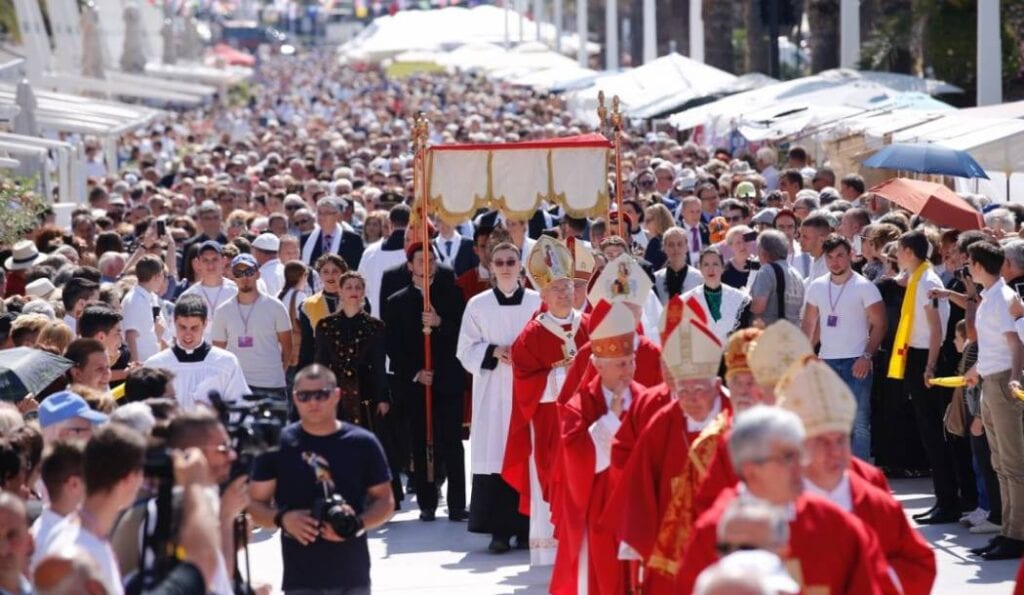 Religious procession with clergy and participants in ceremonial attire walking through a crowded street, a must-see among things to do in Split, Croatia.