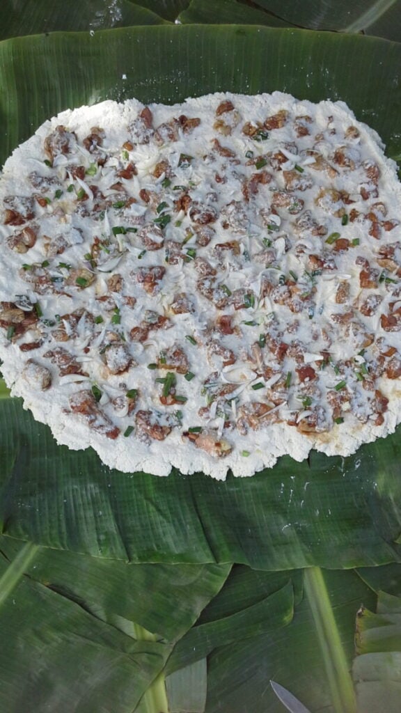 Traditional circular rice cracker, a national dish, with toppings on a banana leaf.
