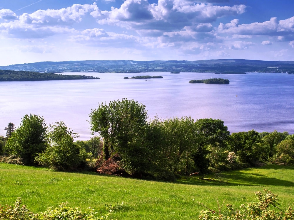 Lough Derg county Tipperary, Nature landscape, Summer day, Cloudy sky. Islands and mountains in the background. A picturesque view of a tranquil lake with scattered islands, surrounded by lush greenery on a clear day, perfect for exploring things to do in Tipperary.