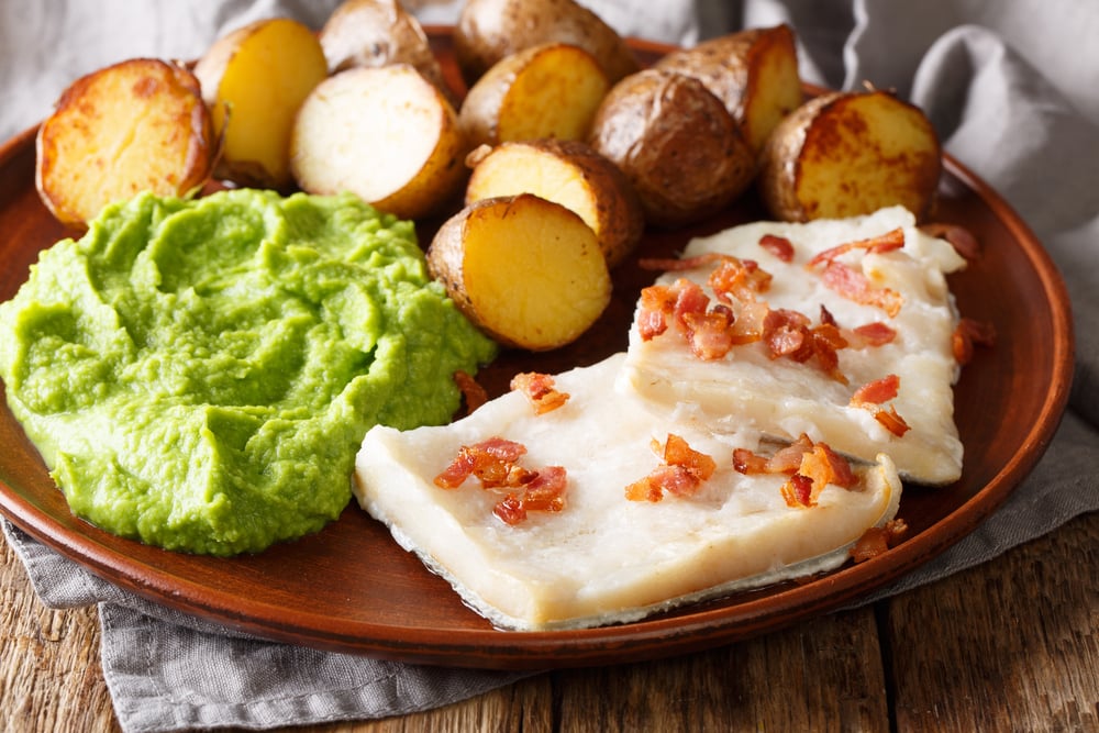 A plate with traditional food in Norway, peas, potatoes, and bacon on it.