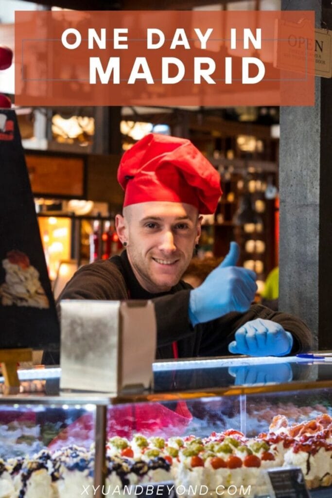 Smiling chef wearing a red hat and blue gloves at a food market during one day in Madrid.
