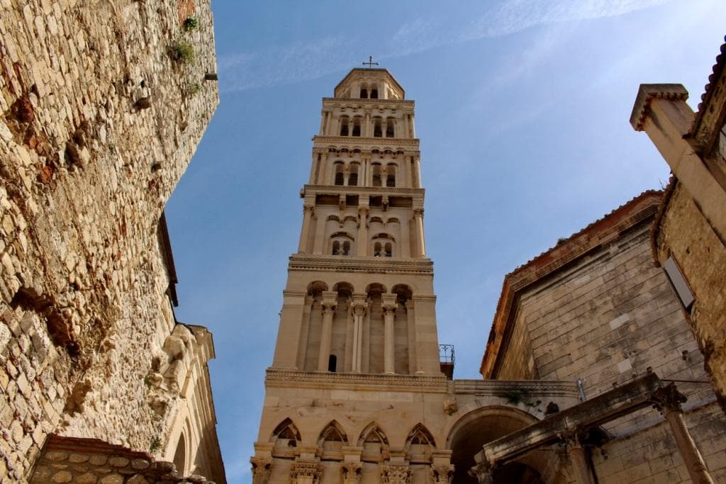 Historic bell tower rising between old stone buildings against a blue sky, a must-see among the things to do in Split, Croatia.