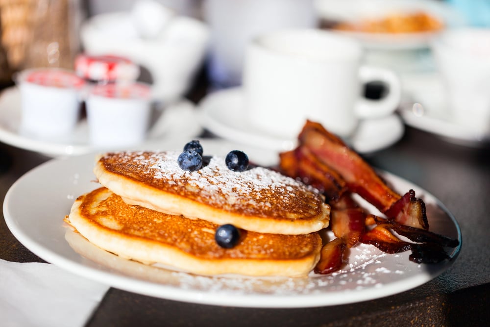 A plate of pancakes with blueberries and bacon, a cherished food in Norway.