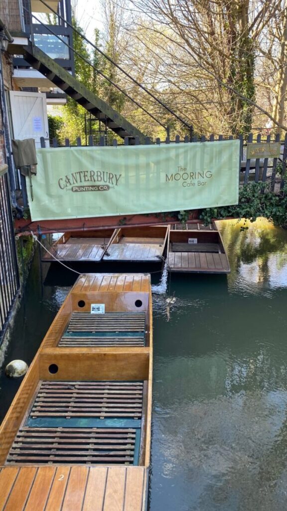 Moored punting boats under a banner for the Canterbury Boat Trips mooring cafe bar.