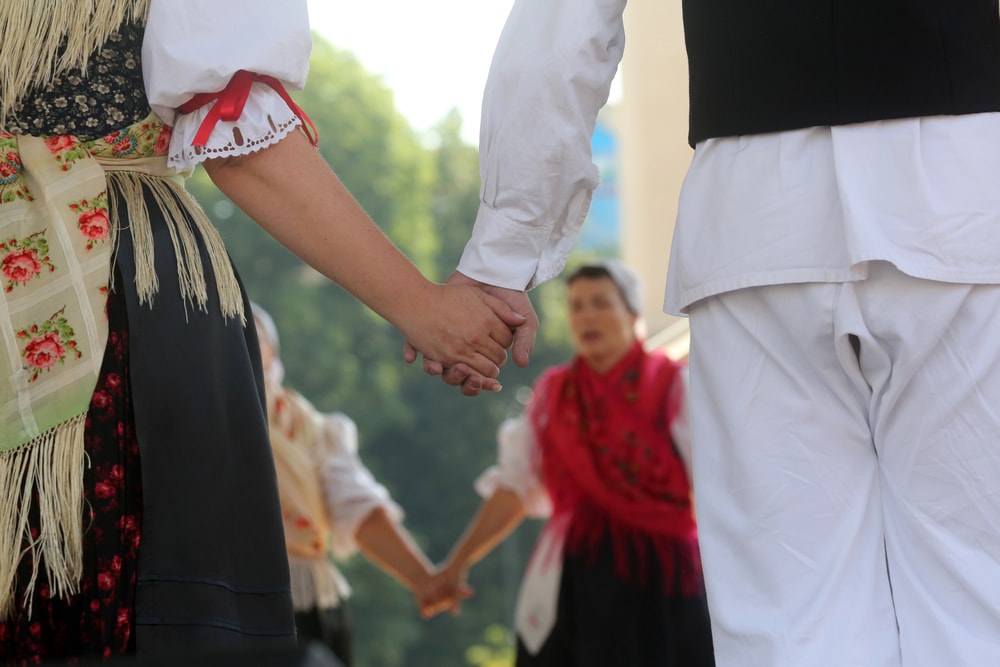 Two people wearing traditional folk costumes hold hands during a dance performance, showcasing things to do in Split, Croatia.