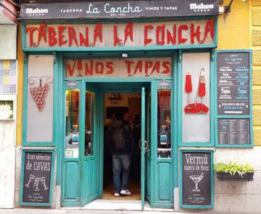 Entrance to "taberna la concha," a one-day-in-Madrid essential tapas and wine bar, with two sandwich boards advertising drinks outside.