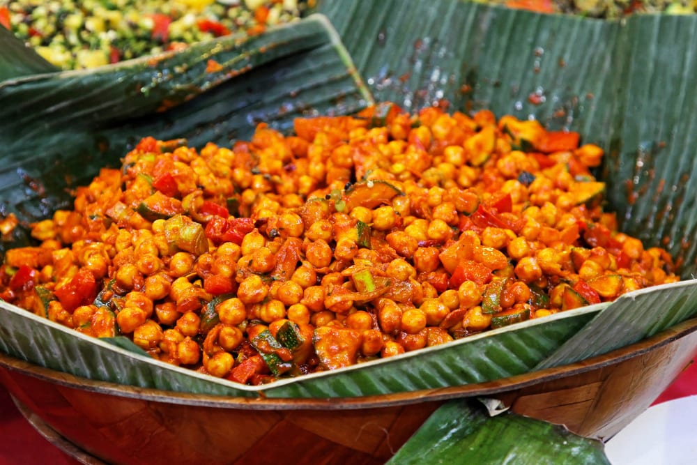 A large serving of spicy chickpea curry displayed on a banana leaf, inspired by West African food.