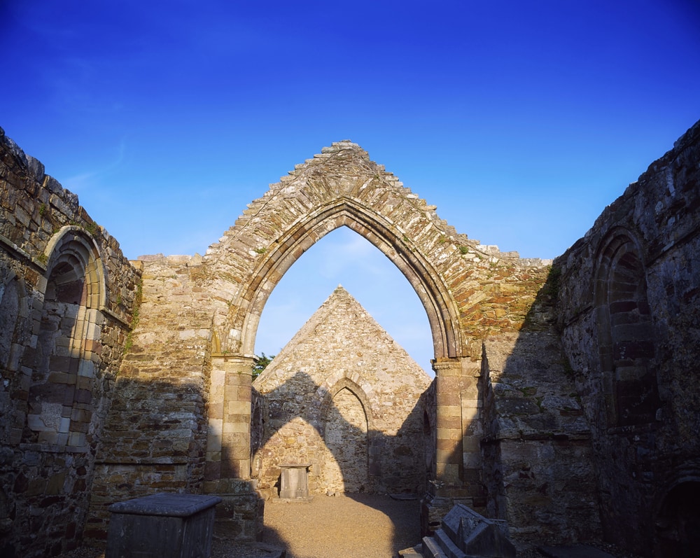 Ruins of a medieval stone archway under a clear blue sky.