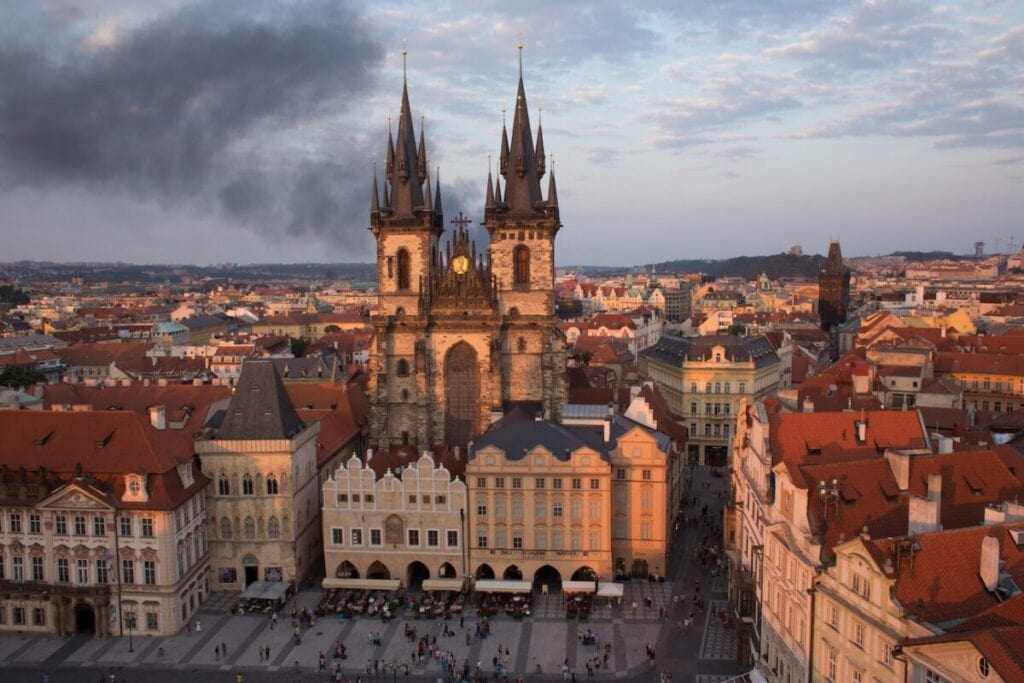 Aerial view of Prague's Old Town Square at sunset, showcasing the iconic gothic towers of the Church of Our Lady before Týn, a must-visit in Prague.