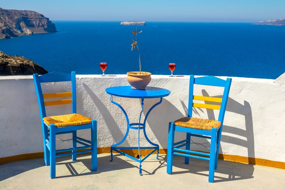 Greece. Santorini. Thira island. Sunny seascape from a cafe in Oia. Two chairs and two glasses of wine