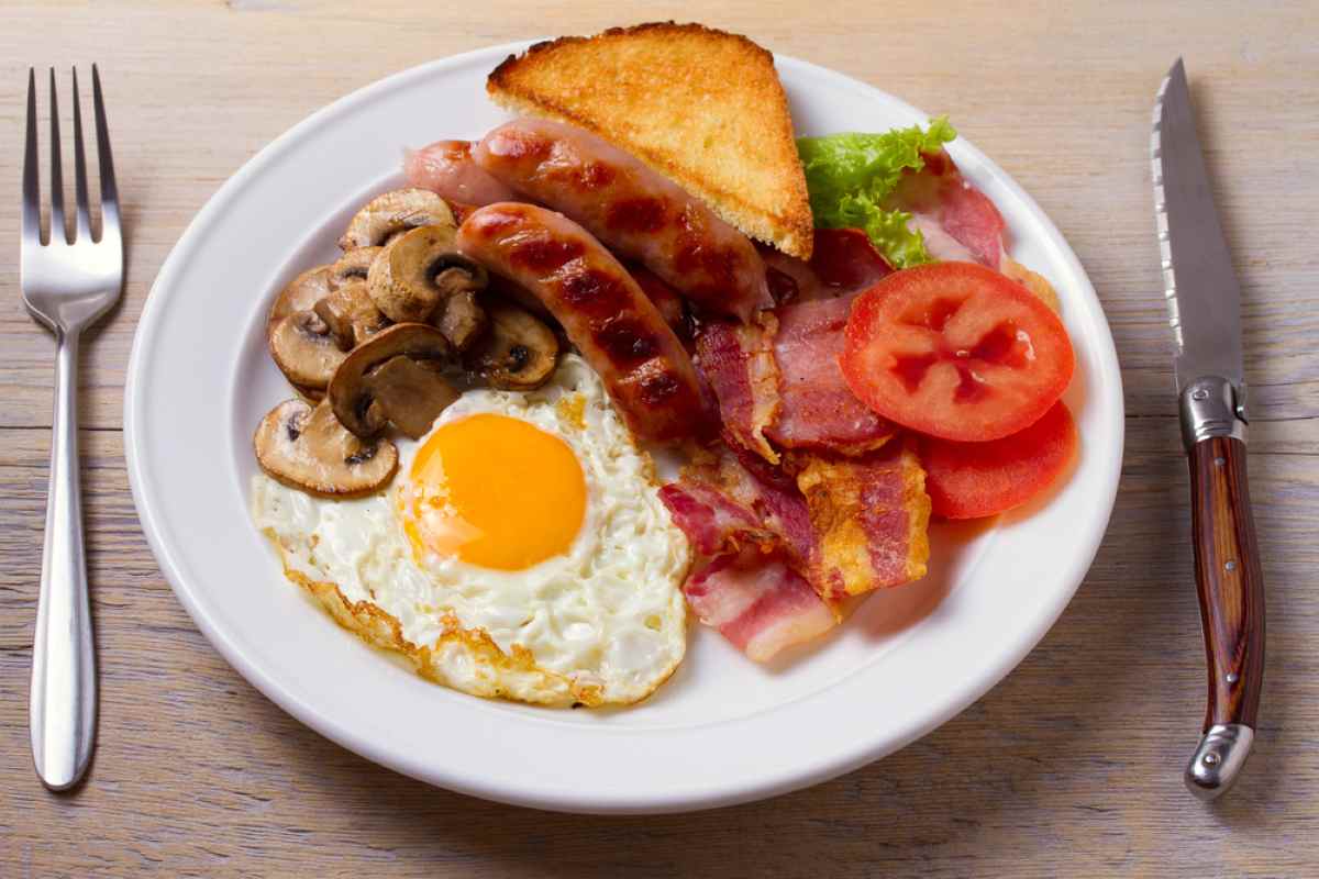 full irish breakfast consists of pot of tea, sausages, eggs, tomato, bacon and mushrooms