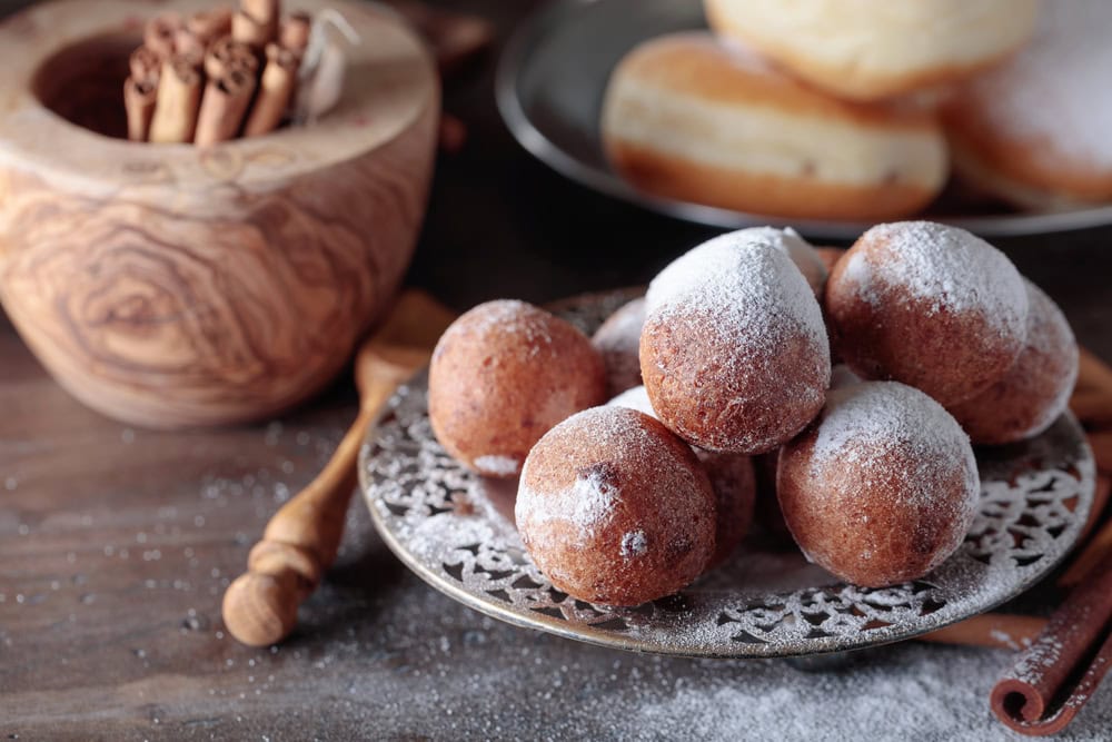 Sweet donuts with cinnamon sticks powdered with sugar on a old wooden table.